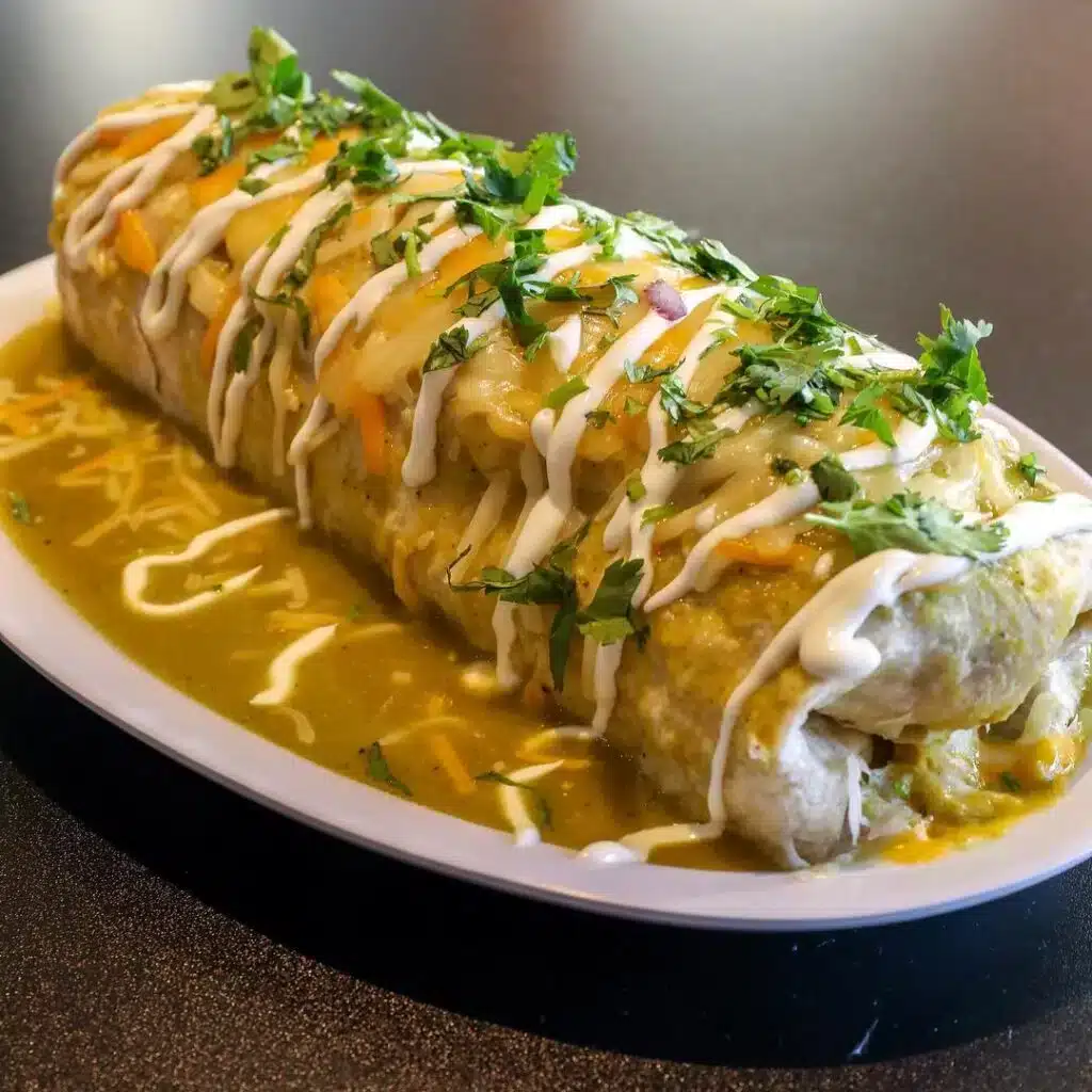 Feed Your Friend for Free — Esmeralda’s 2.0 Border Burrito with Green Salsa in Eureka CA A freshly plated Border Burrito from Esmeralda’s 2.0 in Eureka, California — a wet burrito smothered in green salsa and melted cheese, part of the Burrito BOGO Lunch Special where guests can buy one and gift one free in Humboldt County.