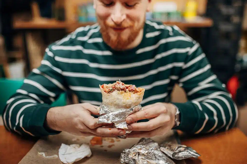 A happy man holding a freshly made burrito from Esmeralda&rsquo;s 2.0 in Eureka, California, showing the Burrito BOGO Lunch Special that lets customers buy one and treat a friend free.