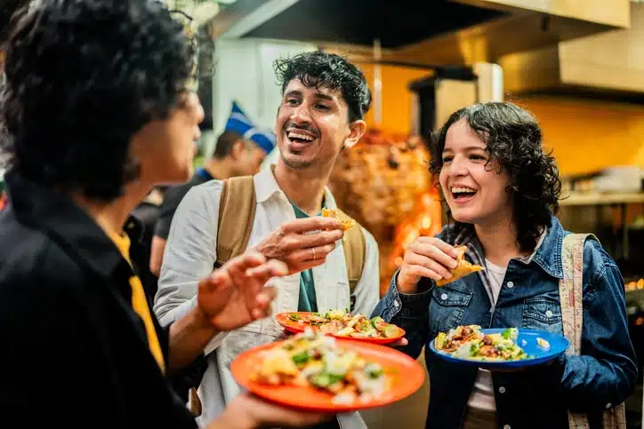Young friends talking and eating taco outdoors Home